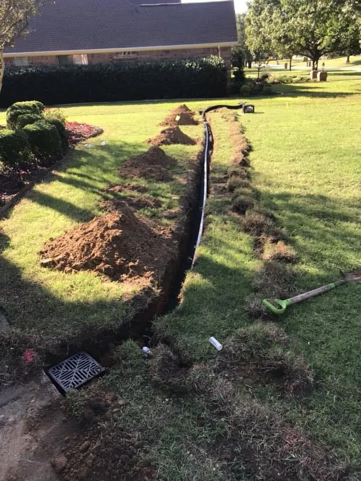 Completed drainage trench work across a lawn