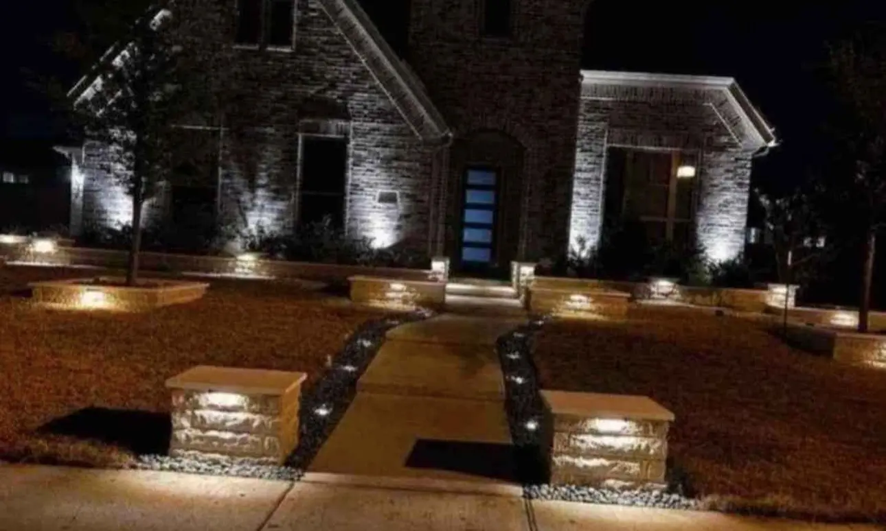 Landscape lighting illuminating stone borders and a residential entry