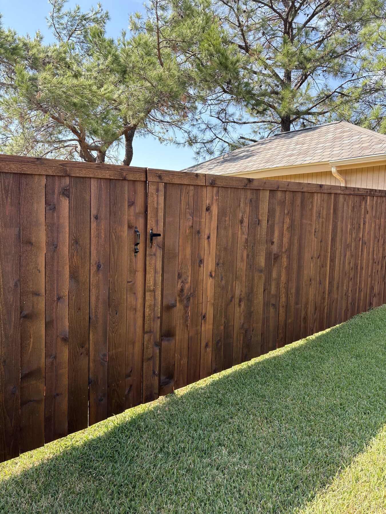 Finished wood privacy fence beside a residential lawn