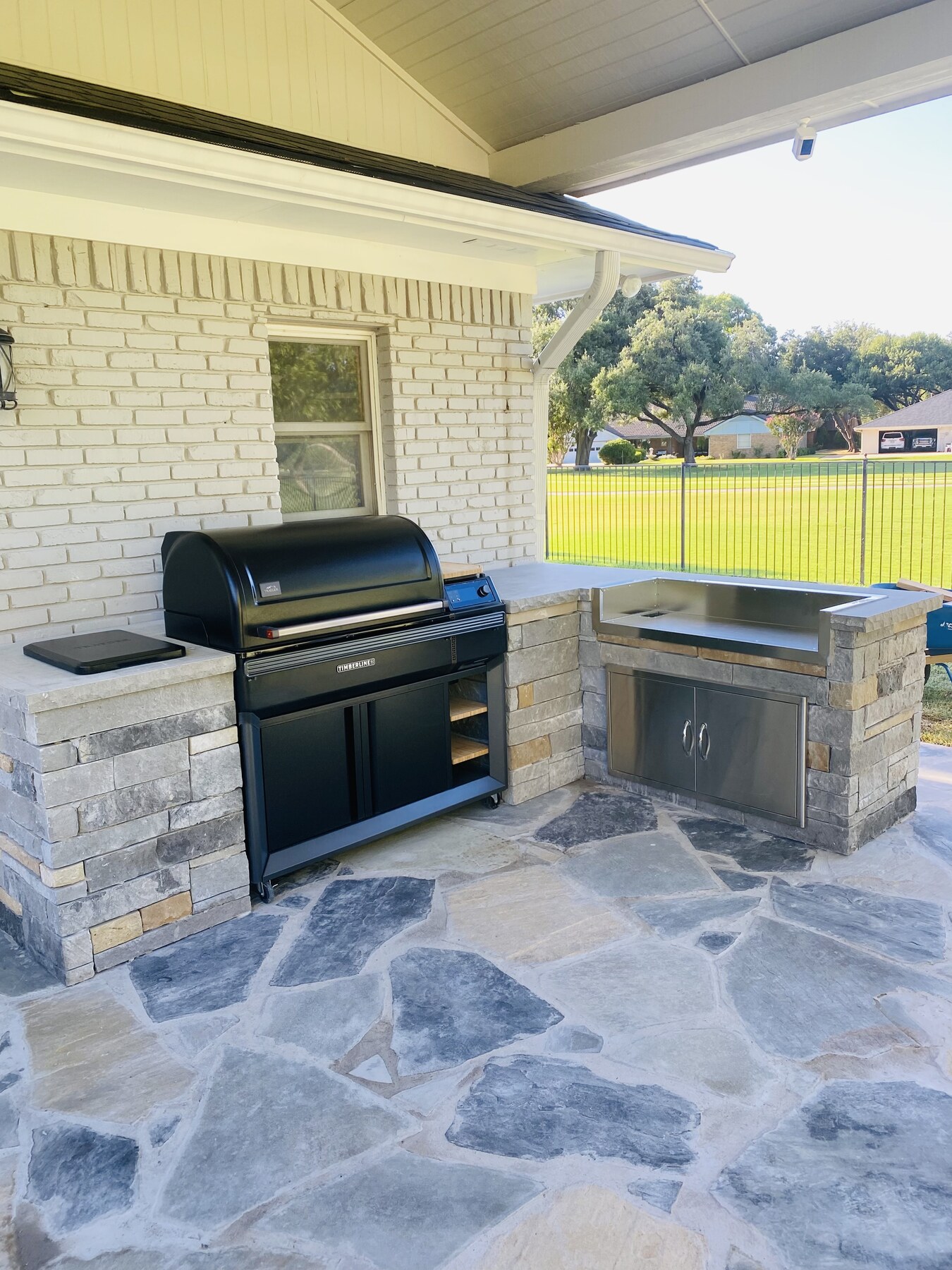 Outdoor kitchen with built-in grill, stone counters and flagstone patio