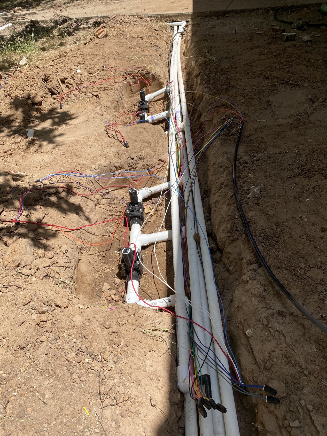 New sprinkler system installation with PVC pipes, valves and wiring